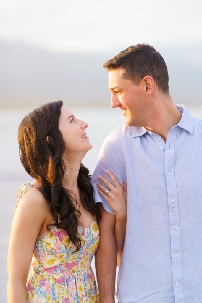 A smiling engaged couple looks into each other’s eyes with love and joy.







