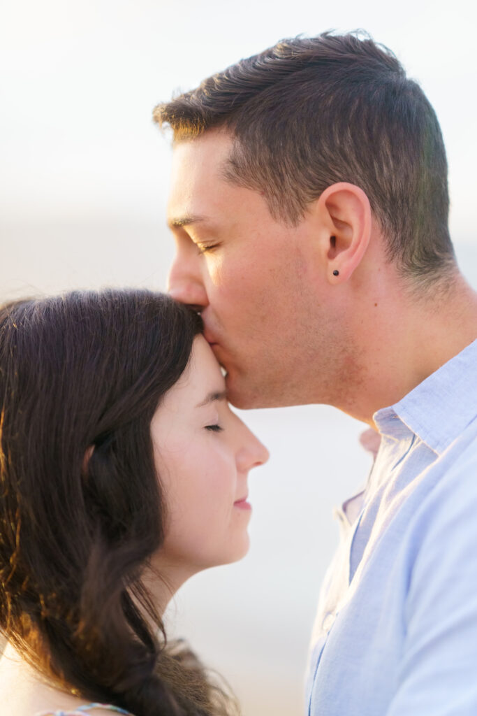 A tender moment captured as he kisses her forehead, reflecting the love of a beautifully intimate Maui proposal.